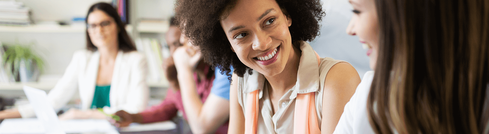 Women smiling at a table in a meeting