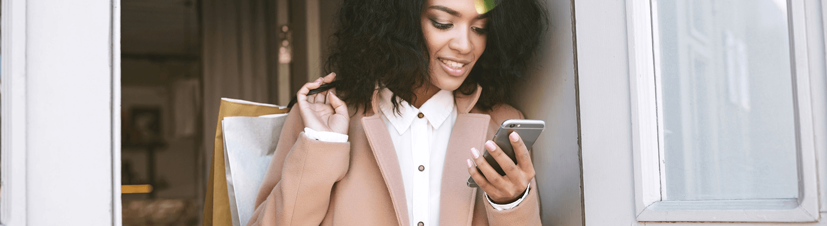 Woman holding shopping bags and a phone.