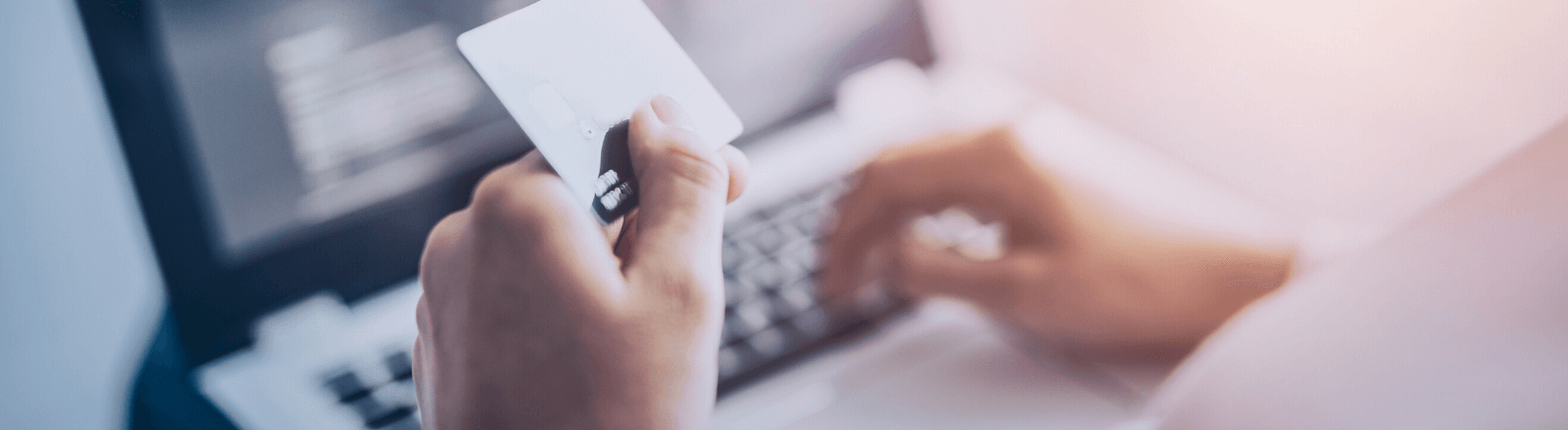 Person holding a check card at a laptop.